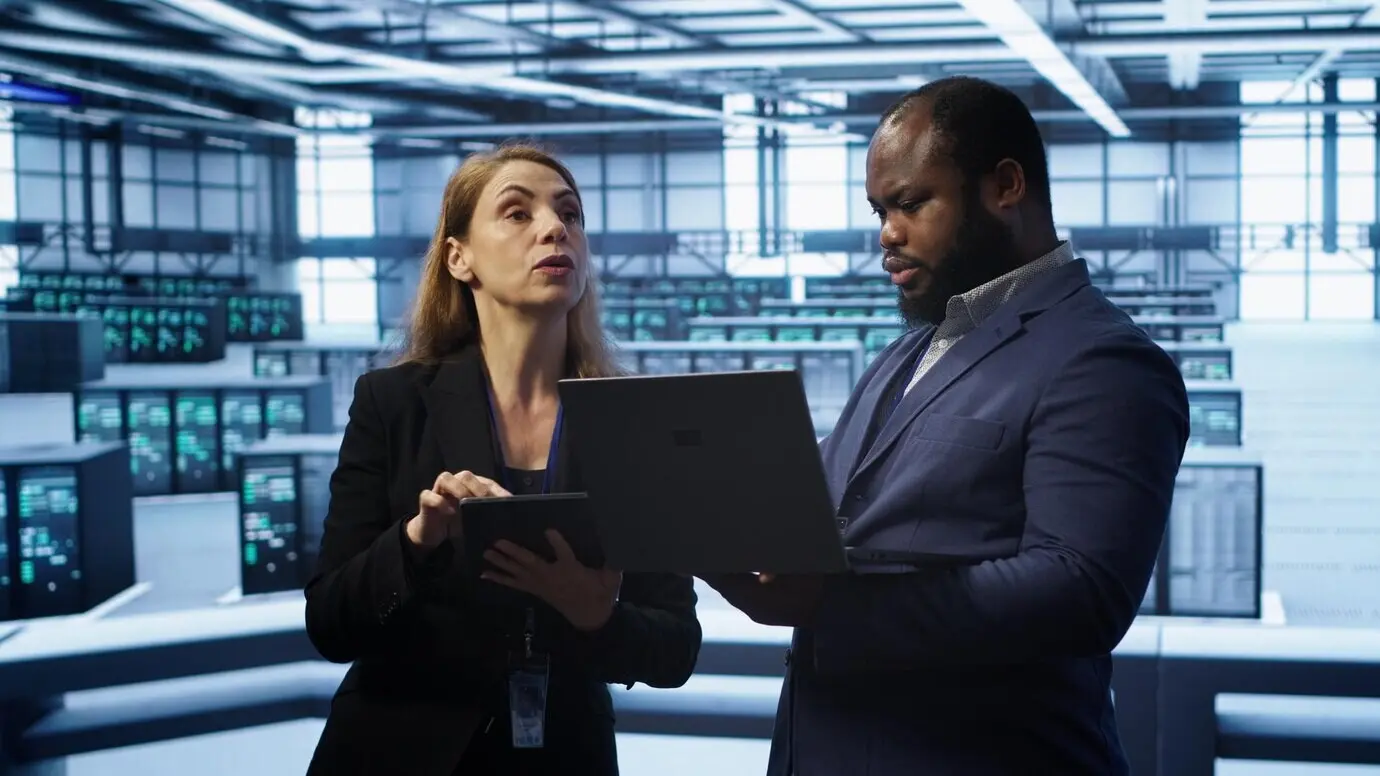 Руководитель на серверной ферме наблюдает за инженером, устраняющим сетевые неполадки.